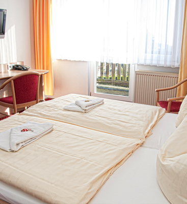 Zimmer im Sporthotel Oberhof mit komfortablem Doppelbett, Fernseher und Balkon