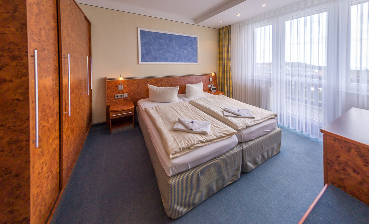 Zimmer im Sporthotel Oberhof mit komfortablem Doppelbett, großem Kleiderschrank und Balkon