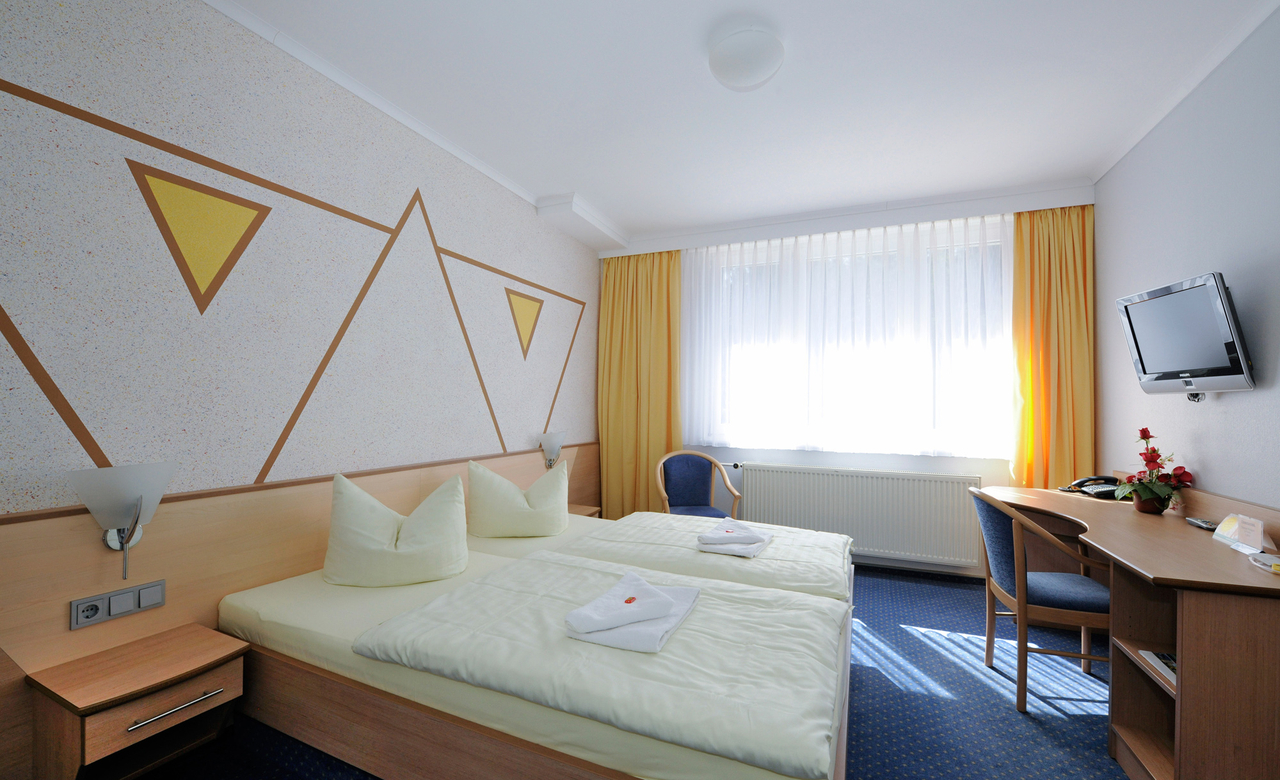 Zimmer im Sporthotel Oberhof mit Doppelbett, Schreibtisch und Fernseher