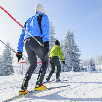 Zwei Skifahrer beim Langlauf durch die verschneite Winterlandschaft im Thüringer Wald