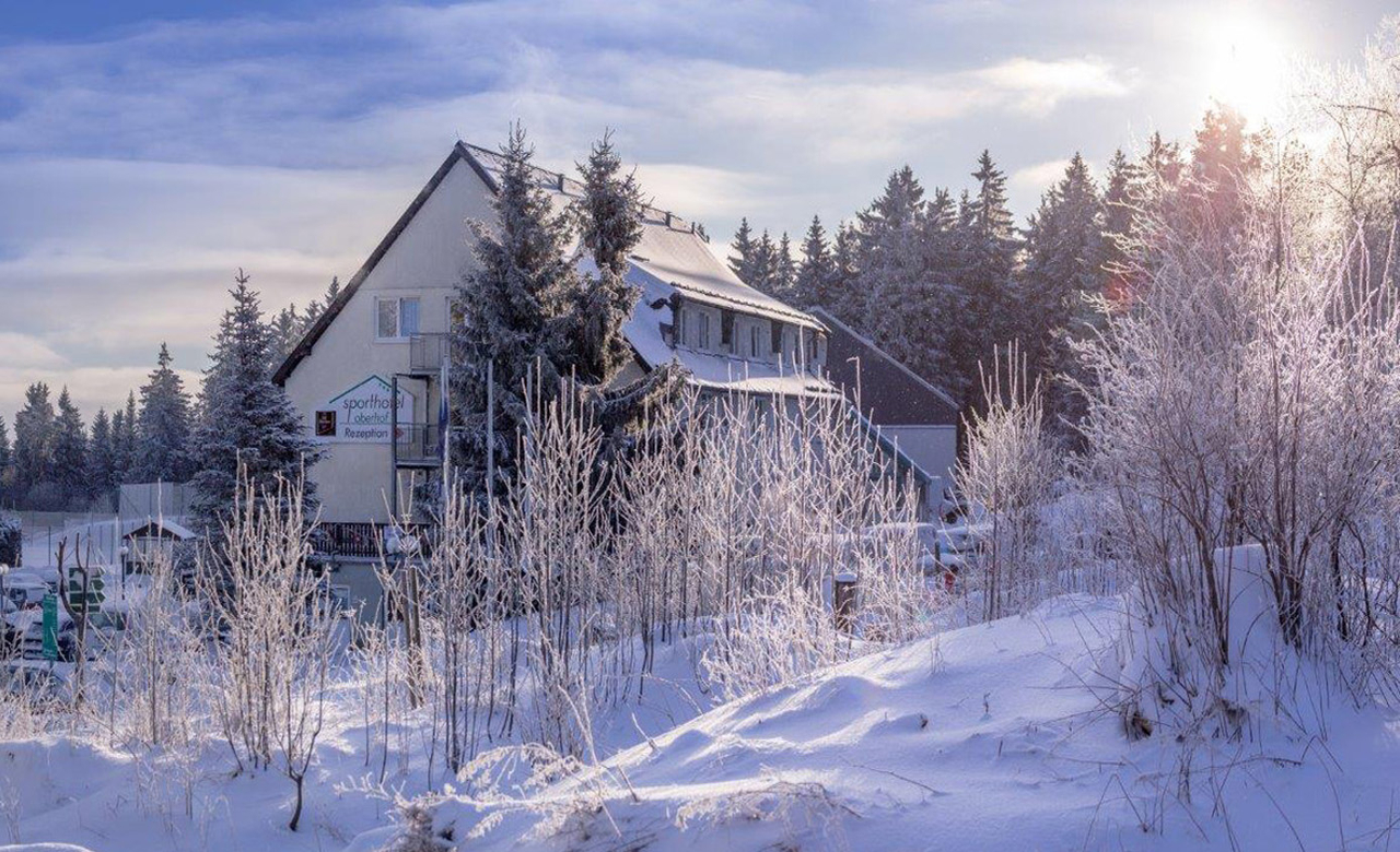 Außenansicht vom Sporthotel Oberhof mit Blick auf die umliegende verschneite Winterlandschaft des Thüringer Waldes