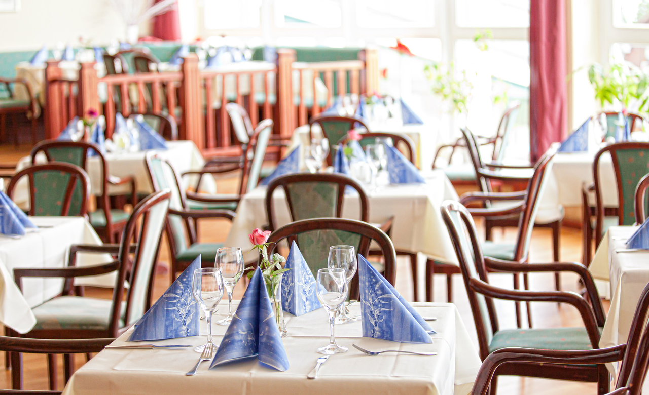 Nahaufnahme eines gedeckten Tischs mit Servietten und einer Rose im Restaurant des Sporthotels Oberhof