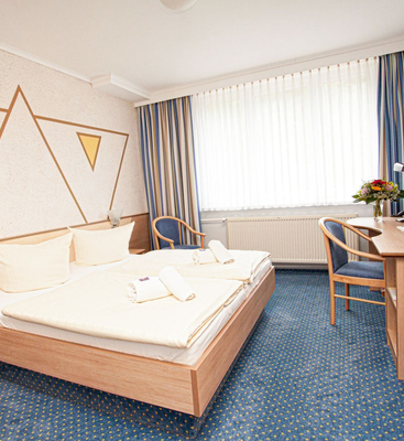helles Classic Zimmer im Sporthotel Oberhof mit komfortablem Doppelbett, Schreibtisch und Fernseher